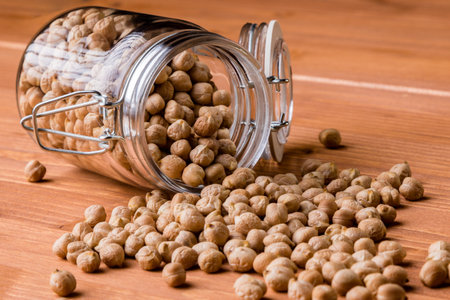 dry brown chickpeas in glass jar on wooden table