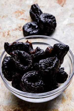 organic sweet dark prunes on steel plateの写真素材