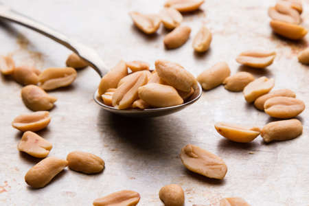 healthy natural brown peanuts on spoon on a steel plateの写真素材