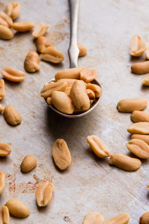 healthy natural brown peanuts on spoon on a steel plateの写真素材