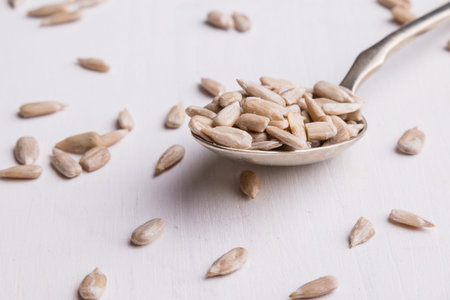 hulled sunflower seeds on spoon on white table