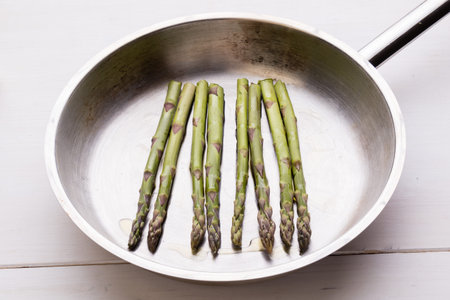 fried green healthy asparagus in frying pan on white tableの写真素材