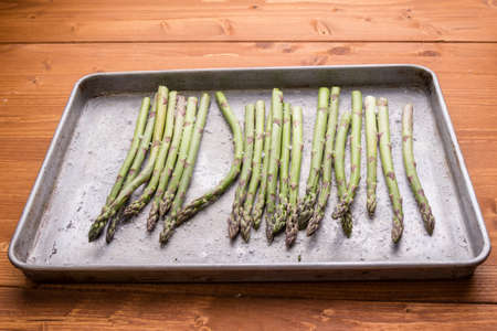 green healthy asparagus in frying pan on wooden table tableの写真素材