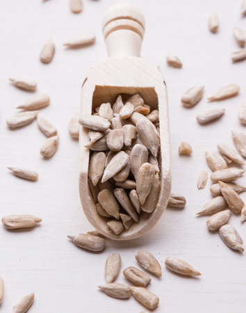 hulled sunflower seeds on wooden scoop on white tableの写真素材