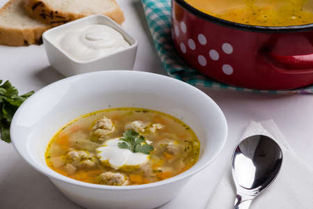 vegetable soup with meatballs on white table in bowlの写真素材