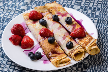 pancakes with jam, syrup and fruits on white plateの写真素材