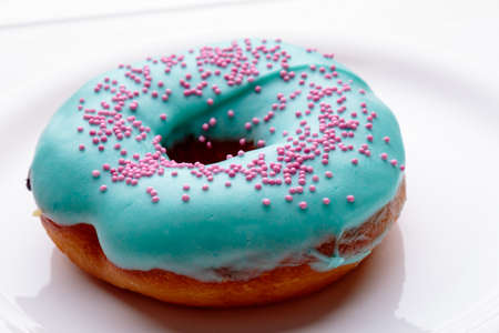 donut with turquoise frosting on white plateの写真素材