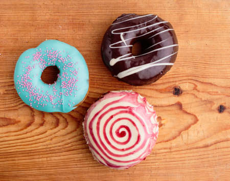 delicious different color donuts on wooden tableの写真素材