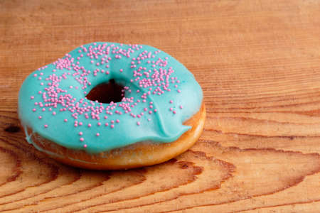 donut with turquoise frosting on wooden tableの写真素材