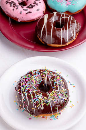 chocolate donut with sprinkles on white plateの写真素材