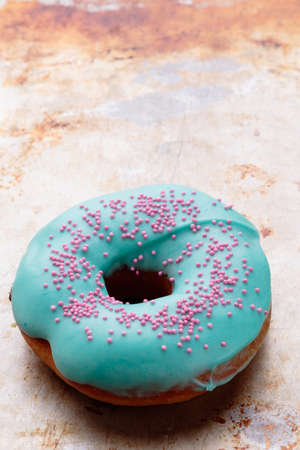 donut with turquoise frosting on steel plateの写真素材