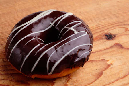 donut with chocolate frosting on wooden tableの写真素材