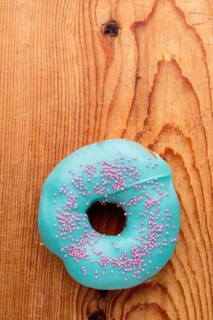 donut with turquoise frosting on wooden tableの写真素材