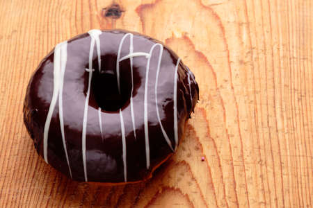 donut with chocolate frosting on wooden tableの写真素材