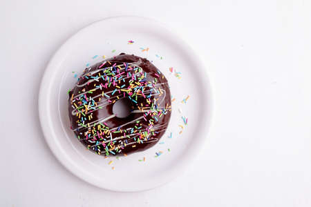 chocolate donut with sprinkles on white plateの写真素材
