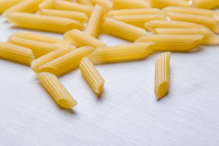 raw uncooked penne pasta on white tableの写真素材