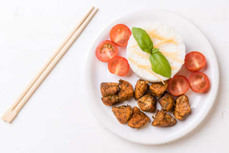 chicken with rice and tomatoes on white plateの写真素材