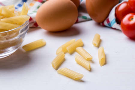 raw uncooked penne pasta on kitchen tableの写真素材