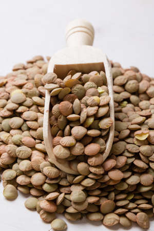 natural organic dry lentils on white table with scoopの写真素材