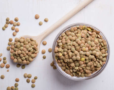 natural organic dry lentils on white table with wooden spoonの写真素材