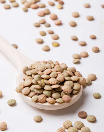 natural organic dry lentils on white table with wooden spoonの写真素材