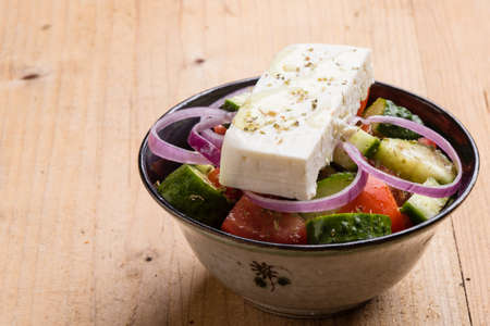 fresh healthy greek salad in bowl on wooden tableの写真素材