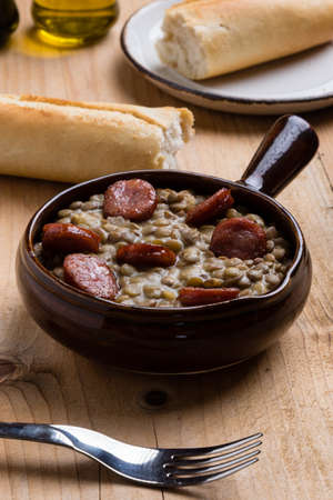 green lentil stew with sausage in brown bowlの写真素材
