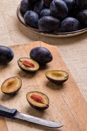 fresh organic tasty plums on cutting board with knife
