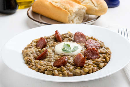 green lentil stew with sausage in white plateの写真素材