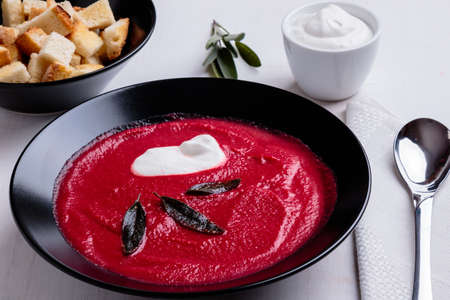 beetroot cream soup in black bowl on white tableの写真素材