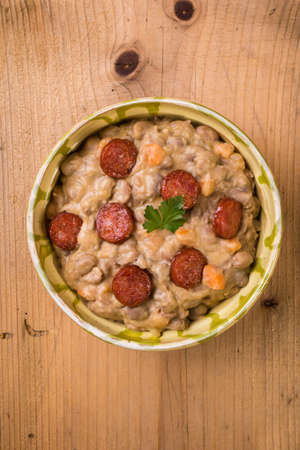 bean stew with sausage on wooden table in rustic settingの写真素材