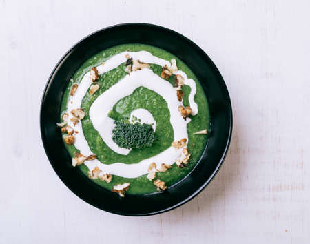 homemade green broccoli cream soup in black bowlの写真素材