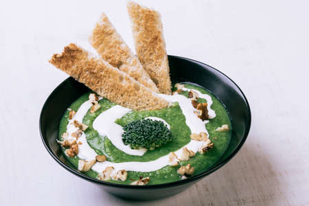 homemade green broccoli cream soup in black bowlの写真素材