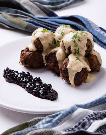 swedish meatballs with blueberry jam on white plateの写真素材