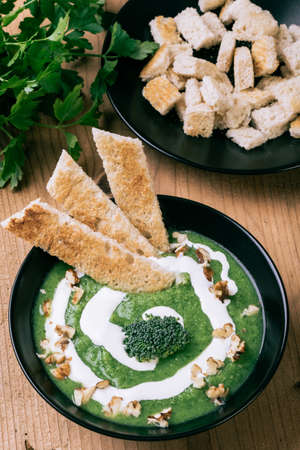 homemade green broccoli cream soup in black bowlの写真素材