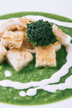 homemade green broccoli cream soup in white plateの写真素材