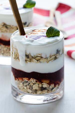 healthy yogurt parfait with jam in glass on white tableの写真素材