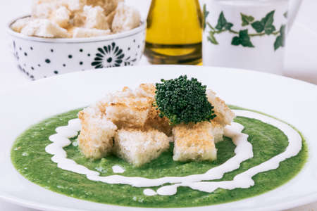 homemade green broccoli cream soup in white plate