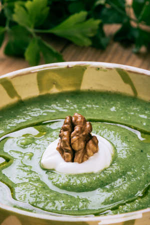homemade green broccoli cream soup with walnutの写真素材