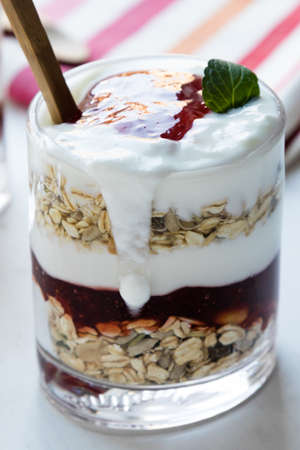 healthy yogurt parfait with jam in glass on white tableの写真素材