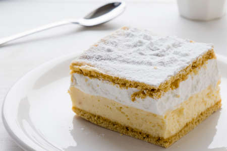 Cream pie with layers of puff pastry on white table
