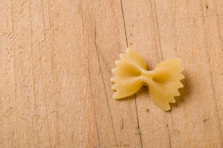 raw farfalle bow-tie pasta on wooden tableの写真素材