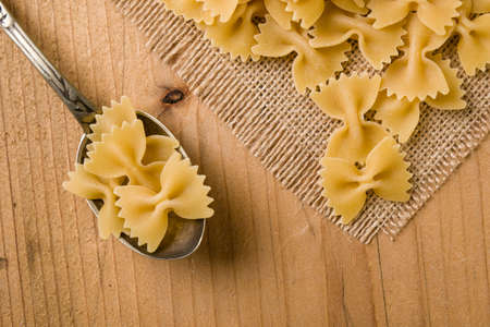 raw farfalle bow-tie pasta on wooden tableの写真素材