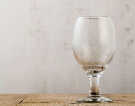 empty beer glass with water droplets on wooden tableの写真素材