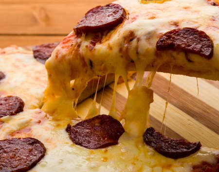 pepperoni pizza slice close up with cheese and salamiの写真素材
