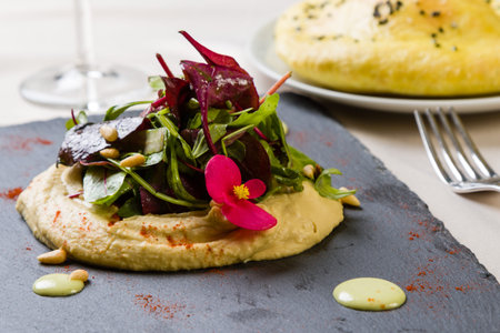 gourmet hummus with salad and bread on black plateの写真素材