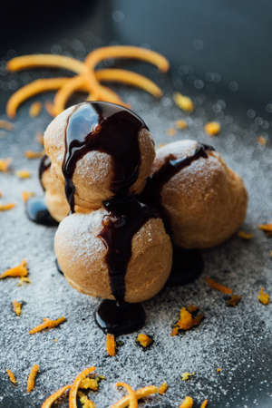 Tasty profiteroles with cream and chocolate glaze on a plateの写真素材