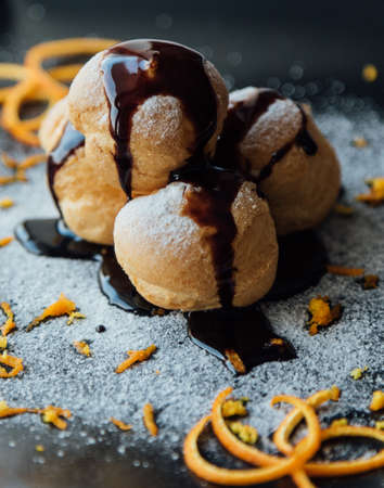 Tasty profiteroles with cream and chocolate glaze on a plateの写真素材