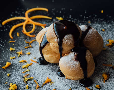 Tasty profiteroles with cream and chocolate glaze on a plateの写真素材