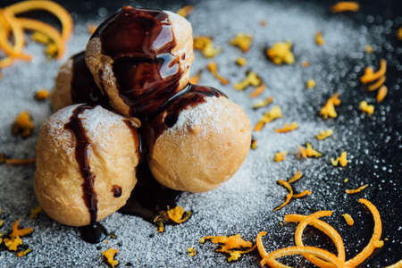 Tasty profiteroles with cream and chocolate glaze on a plateの写真素材